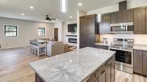 A modern kitchen with granite countertops, stainless steel appliances, and dark wooden cabinets. - Modern Kalispell Retreat: 37 Mi to Glacier NP (Kalispell)