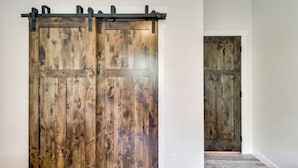 A wooden sliding door with a metal track, a plain white wall, and a carpeted floor. - Modern Kalispell Retreat: 37 Mi to Glacier NP (Kalispell)