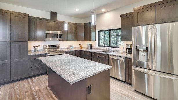 A modern kitchen with dark wood cabinets, stainless steel appliances, and a granite countertop. - Modern Kalispell Retreat: 37 Mi to Glacier NP (Kalispell)