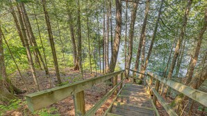 A wooden bridge in a forested area with a river in the background. - Waterfront Escape on Caribou Lake: Dock + Fire Pit (Lutsen)