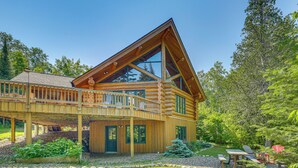 A log cabin with a balcony, a deck, and a garden area with a table and chairs. - Waterfront Escape on Caribou Lake: Dock + Fire Pit (Lutsen)