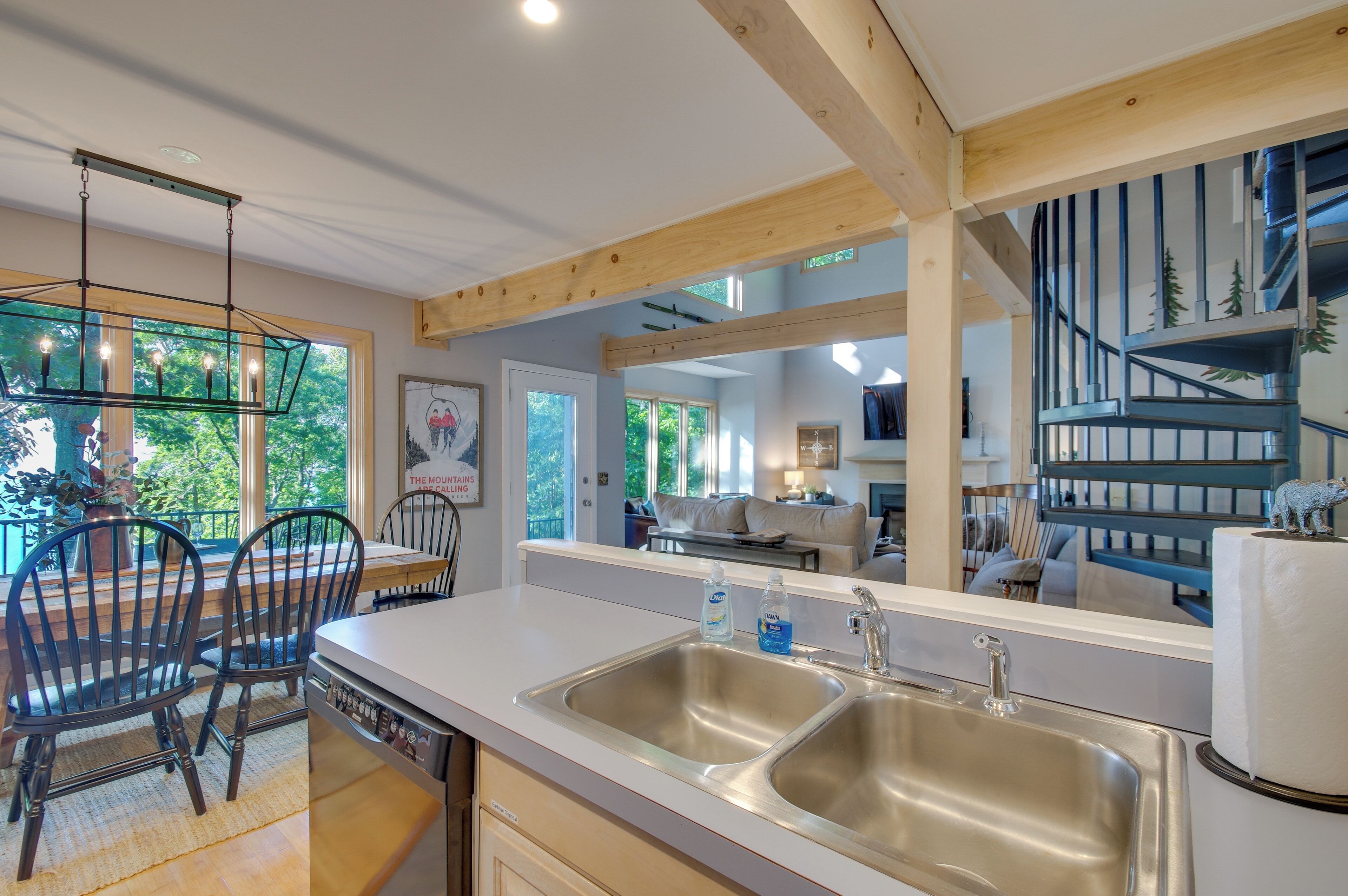 A modern kitchen with a large island, stainless steel sinks, and a dining area with chairs.