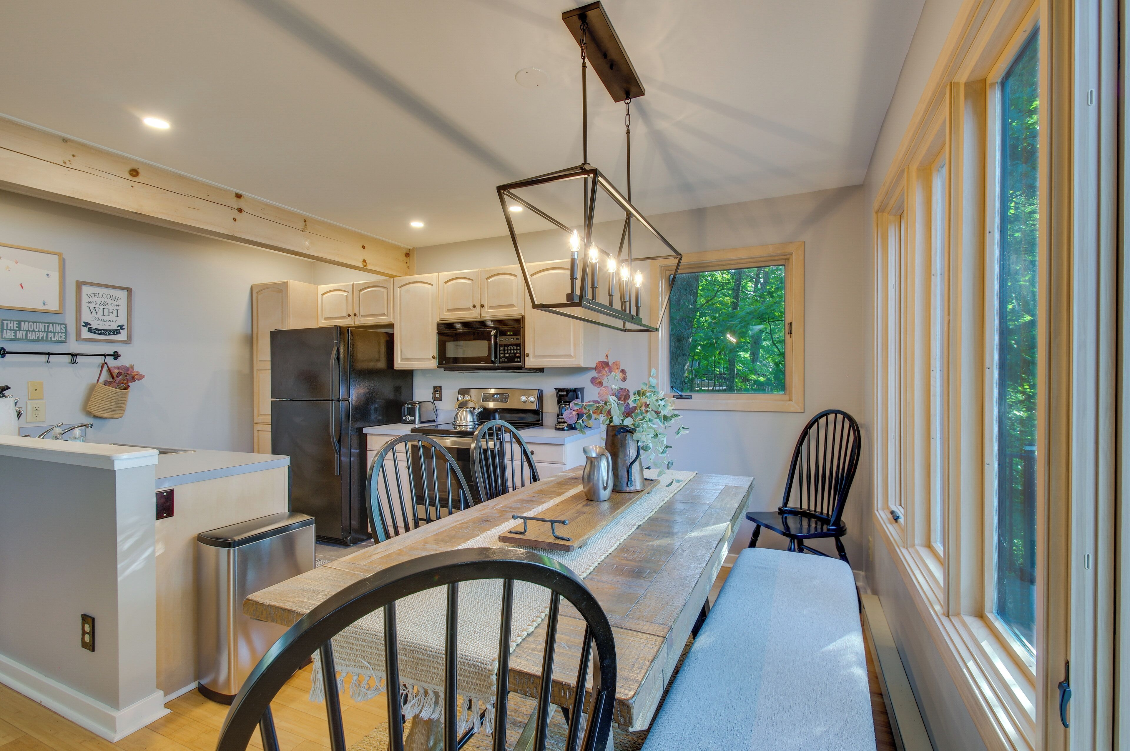 A modern kitchen with a central island, stainless steel appliances, and a large window providing natural light.