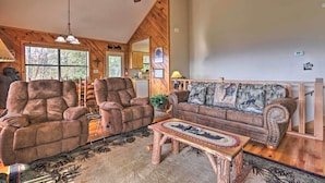 A cozy living room with a wooden ceiling, a ceiling fan, a large window, and a fireplace. - Smoky Mountain Retreat w/ Hot Tub, Arcade Games (Sevierville)