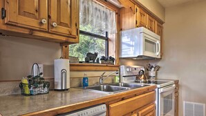 A kitchen with wooden cabinets, a built-in microwave, a dishwasher, and a sink. - Smoky Mountain Retreat w/ Hot Tub, Arcade Games (Sevierville)