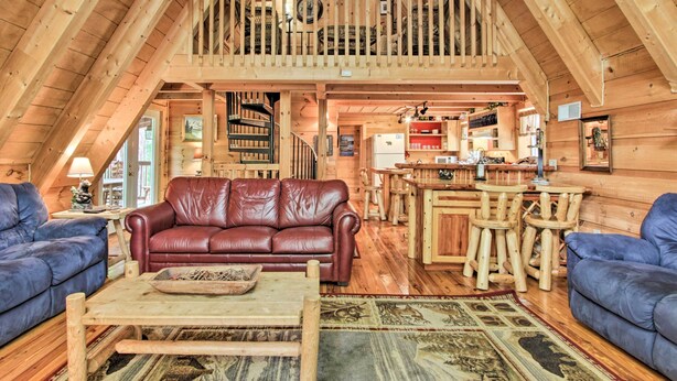 A cozy wooden cabin interior with a loft bedroom, a living room with a leather sofa, and a kitchen area. - A-frame Cabin w/ Hot Tub < 1 Mi to Ober Gatlinburg (Gatlinburg)