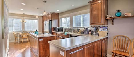 A modern kitchen with wooden cabinets, a central island, and a dining area with a table and chairs.