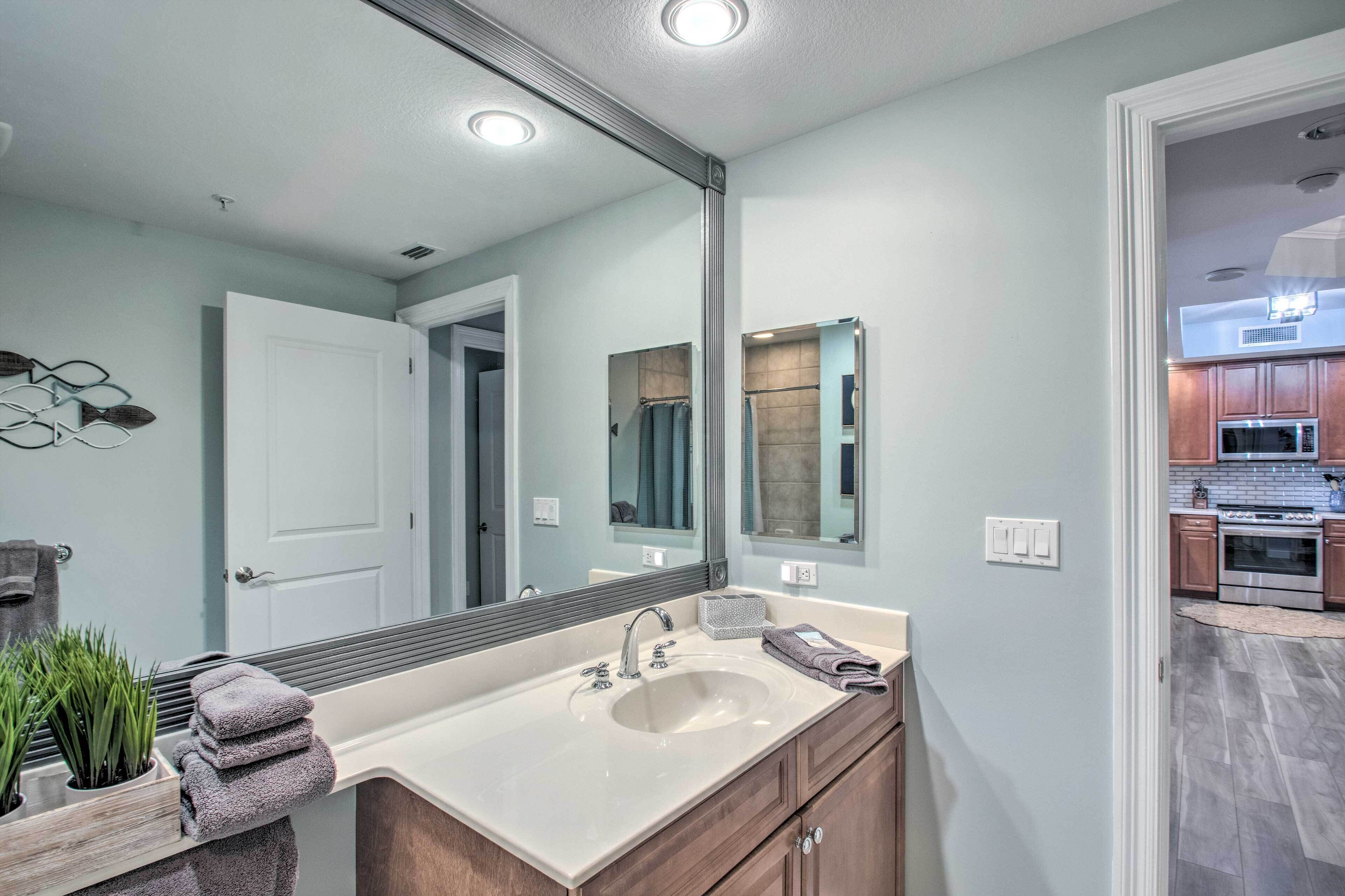 Une salle de bain avec un grand miroir, un lavabo et des meubles en bois.