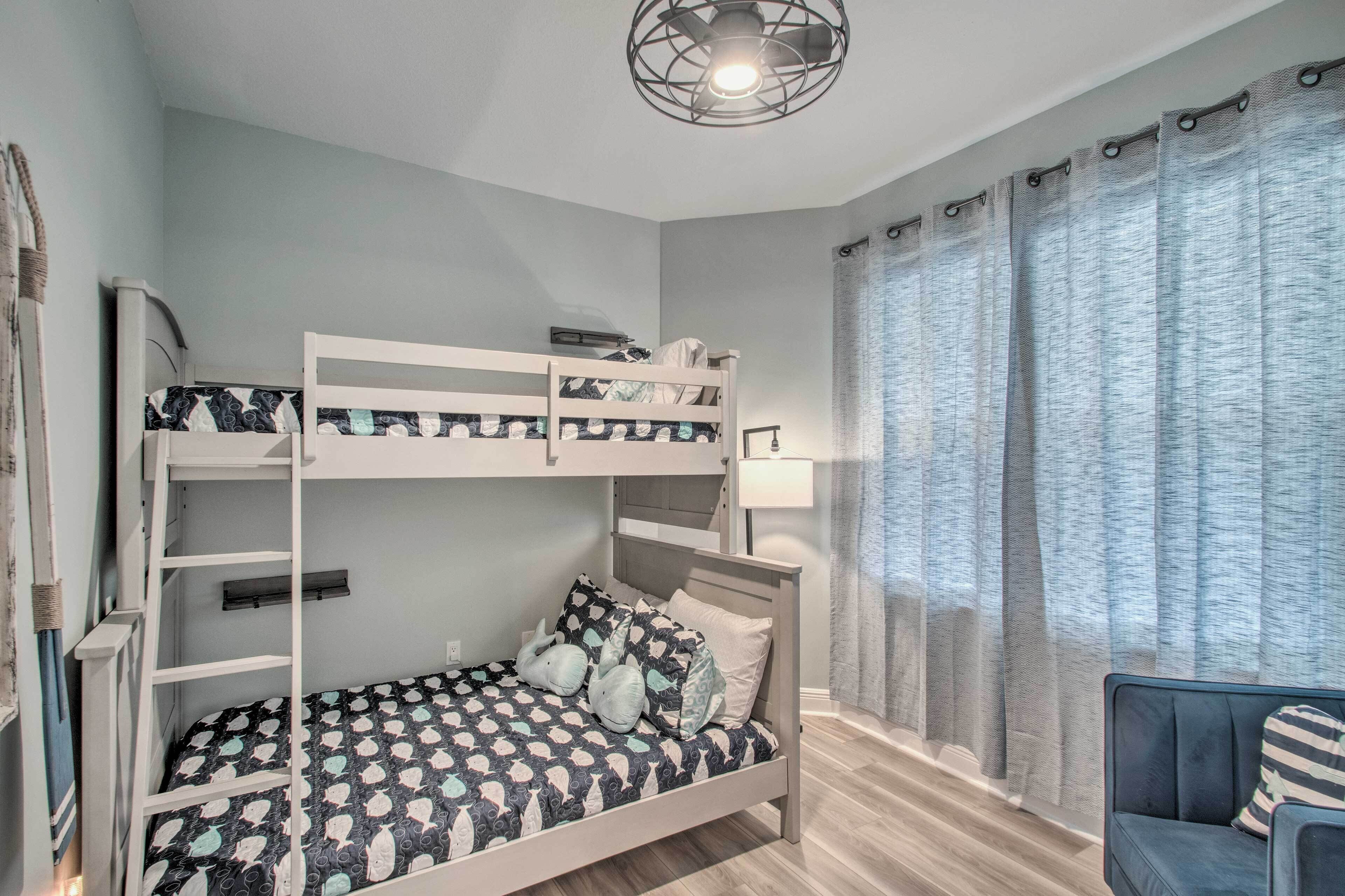 Een stapelbed met behang, een bureau, een stoel en een lamp.