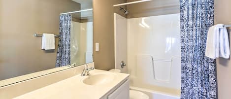 Un baño con un espejo grande, un lavamanos, un inodoro y una ducha.