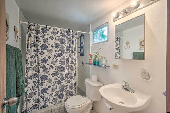 A bathroom with a shower curtain, toilet, sink, and a mirror. - Island Apt w/ Panoramic Ensenada Honda View! (Culebra)