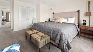 Un dormitorio con cama, banca, mesita de noche y lámpara colgante.