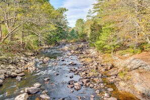 A river flowing through a forest with a bridge in the distance.