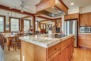 A spacious kitchen with wooden cabinets, a large island, stainless steel appliances, and a dining area with wooden furniture.
