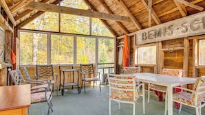 Een houten chalet met een overdekte veranda, ingericht met stoelen en een tafel, en een bord met de tekst 'BEMIS-SC'.