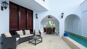 A covered outdoor seating area with a pool, featuring a dining table and chairs, and a sofa with cushions. - 2min to Beach Rooftop Terrace 360 Views Pool BBQ - Casa Cazenovia 3BR (Tempate)
