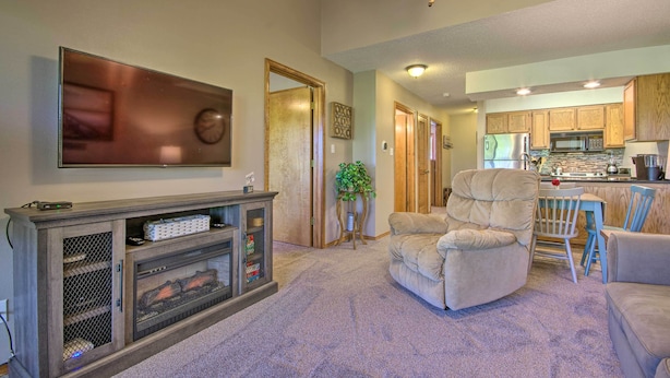 A living room with a fireplace, a television, and a dining area with a kitchen in the background. - Cozy Branson Getaway ~ 2 Mi to Silver Dollar City! (Branson West)