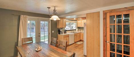A dining area with a wooden table and chairs, a kitchen with wooden cabinets, and a glass door leading outside.