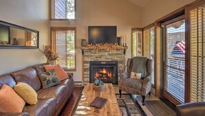 A cozy living room with a stone fireplace, leather sofa, and patterned armchair.