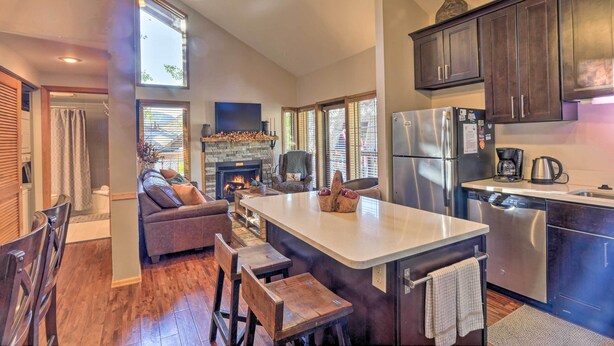 A modern kitchen with a central island, dark wooden cabinets, stainless steel appliances, and a fireplace.