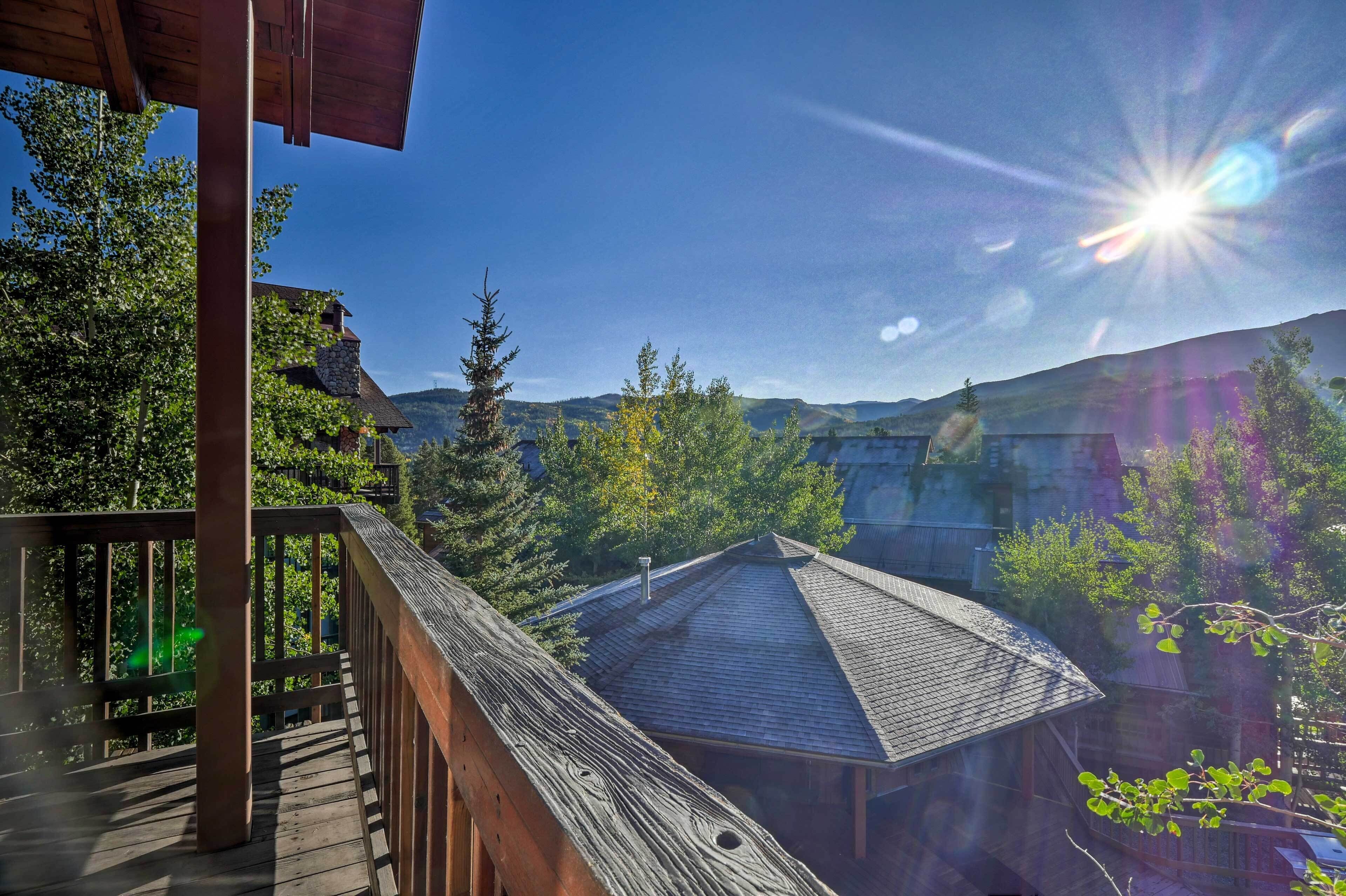 A wooden deck with a view of a mountain landscape and a building with a sloped roof.