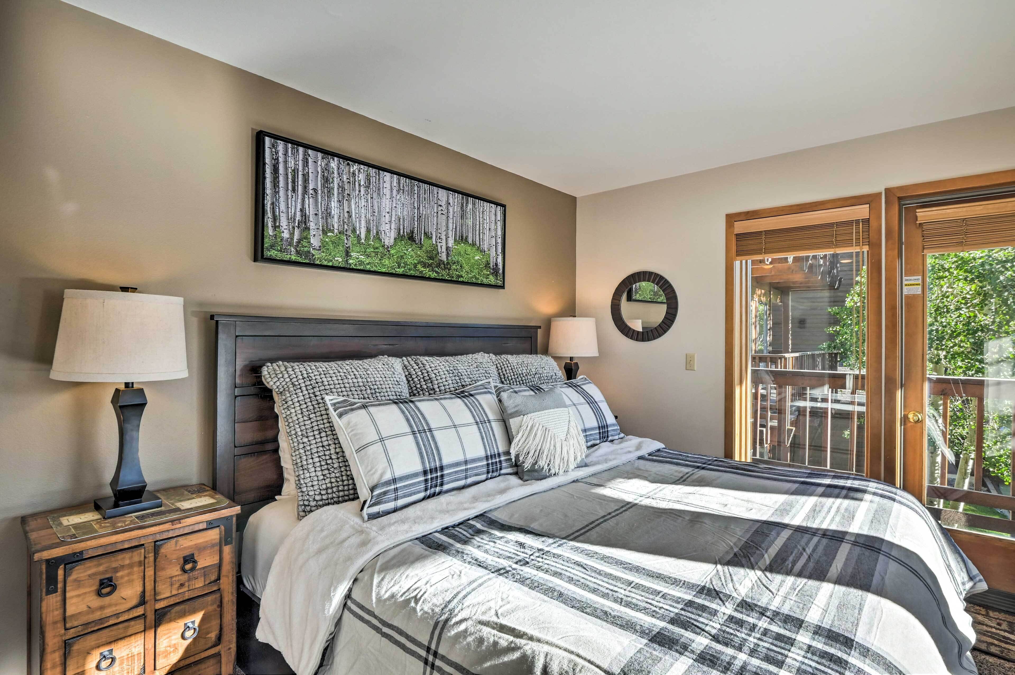 Une chambre à coucher comprenant un lit, une table de chevet, un miroir fixé au mur et une fenêtre donnant sur un paysage verdoyant.