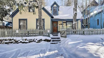 A two-story house with a snow-covered roof and a wooden picket fence.