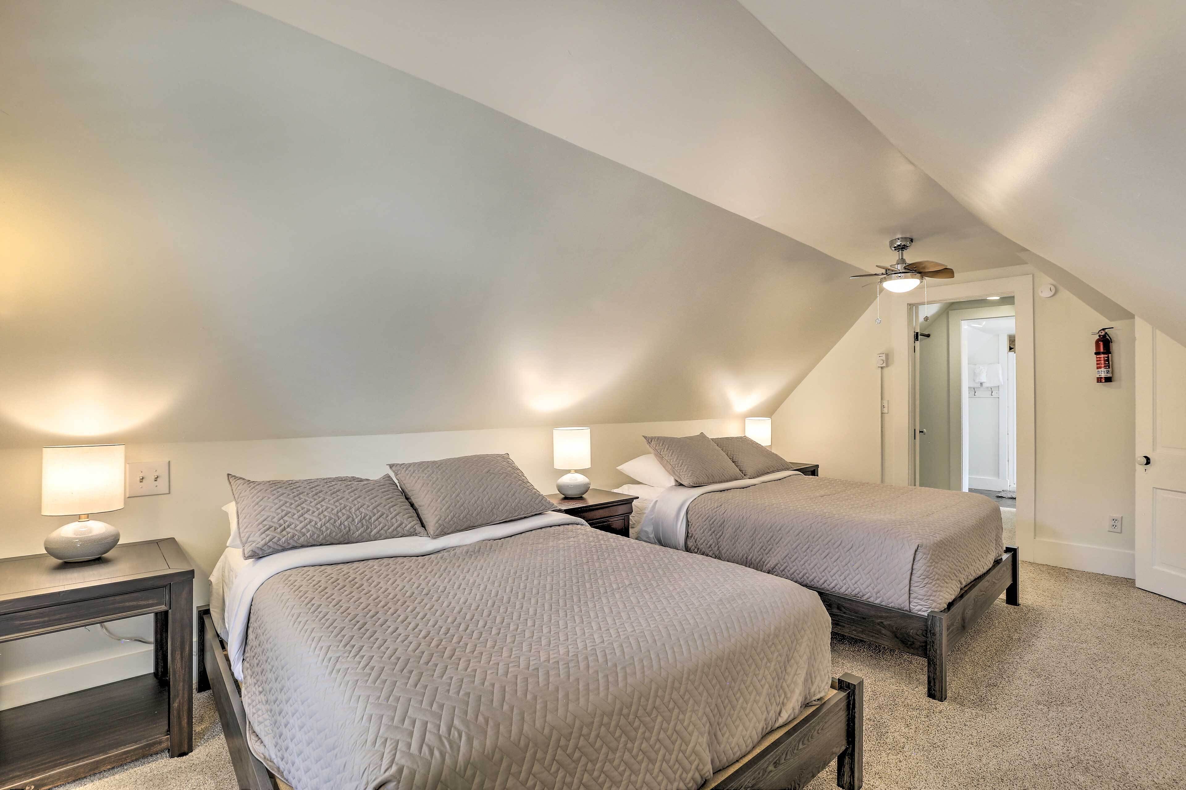 A bedroom with two beds, a ceiling fan, and a fire extinguisher.