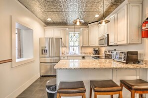 A kitchen with white cabinets, stainless steel appliances, a granite countertop, and a central island with stools. - Close to Main St & Slopes: Breck Home w/ Hot Tub! (Breckenridge)