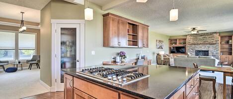 A spacious kitchen with wooden cabinets, a central island, and pendant lighting.