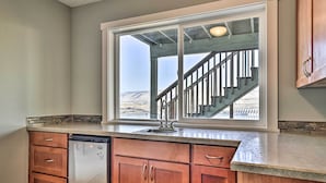 A kitchen with wooden cabinets, a built-in dishwasher, and a window overlooking a staircase.