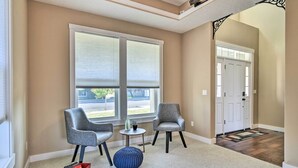 A room with two grey armchairs, a small round table with a vase, and a blue ottoman.