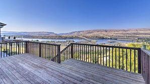 A wooden deck with a view of a river and mountains.