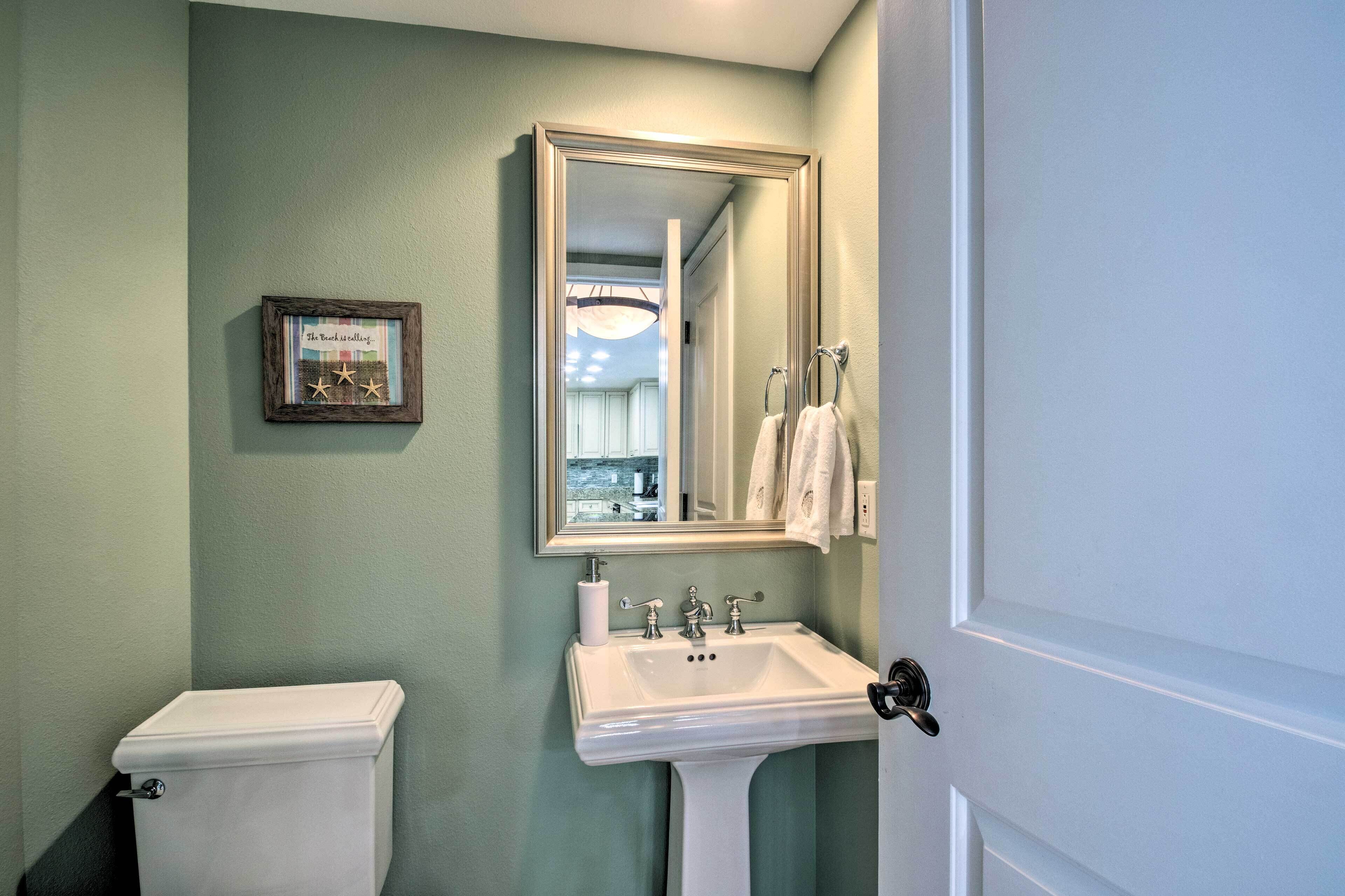 A bathroom with a toilet, sink, and a mirror.