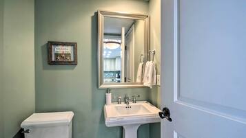 A bathroom with a toilet, sink, and a mirror.