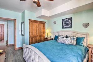 A bedroom with a large bed, wooden wardrobe, and a ceiling fan.