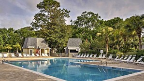 A swimming pool with lounge chairs and two small buildings with sloped roofs, surrounded by trees. - 1 Mi to Beach: Family-friendly Evian Resort Condo! (Hilton Head Island)