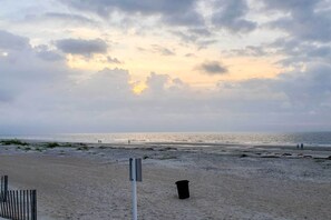 A beach with a wooden fence, a trash bin, and a signpost. - 1 Mi to Beach: Family-friendly Evian Resort Condo! (Hilton Head Island)