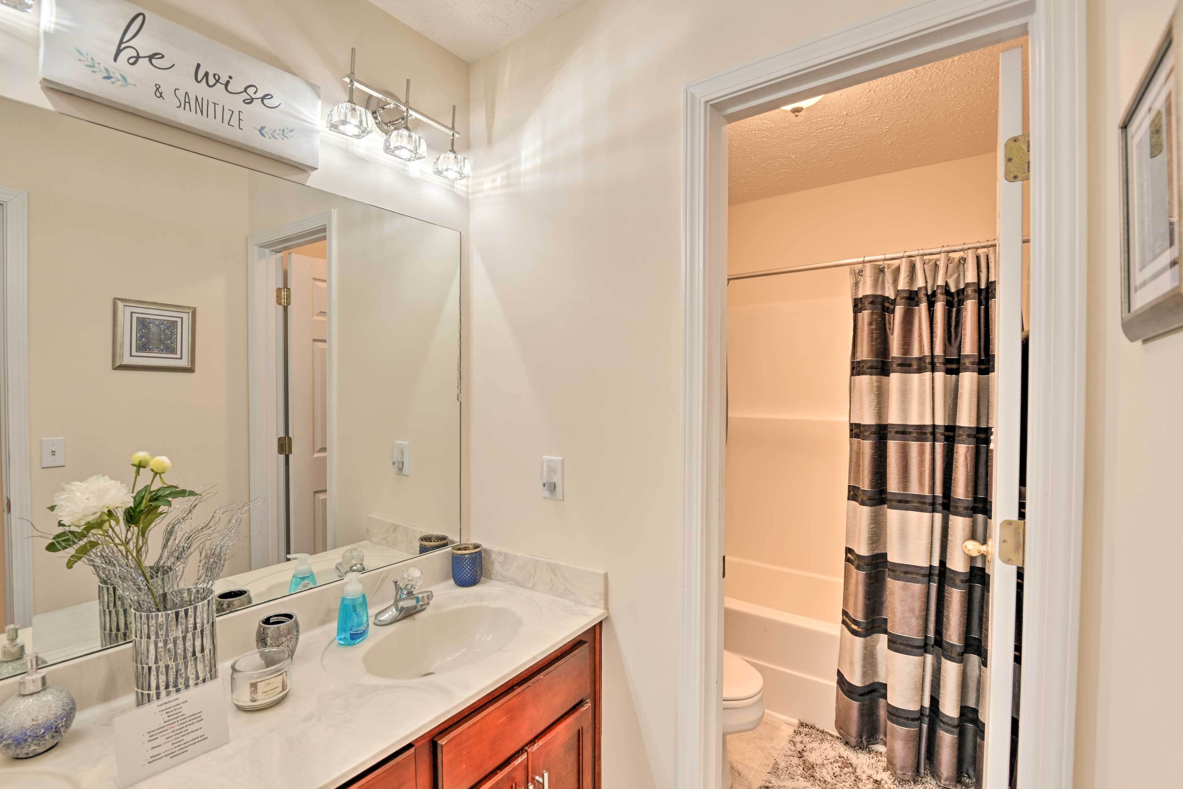 A bathroom with a vanity, mirror, and a shower curtain.