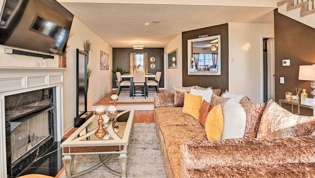 A living room with a fireplace, a sofa, a dining area, and a TV mounted on the wall. - Charming Nashville Home ~ 6 Mi to Downtown! (Nashville)