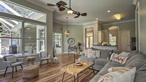 A spacious living room with a large sectional sofa, a wooden coffee table, and a ceiling fan. - Upscale Palm Coast Home w/ Pool: 7 Mi to Beaches! (Palm Coast)
