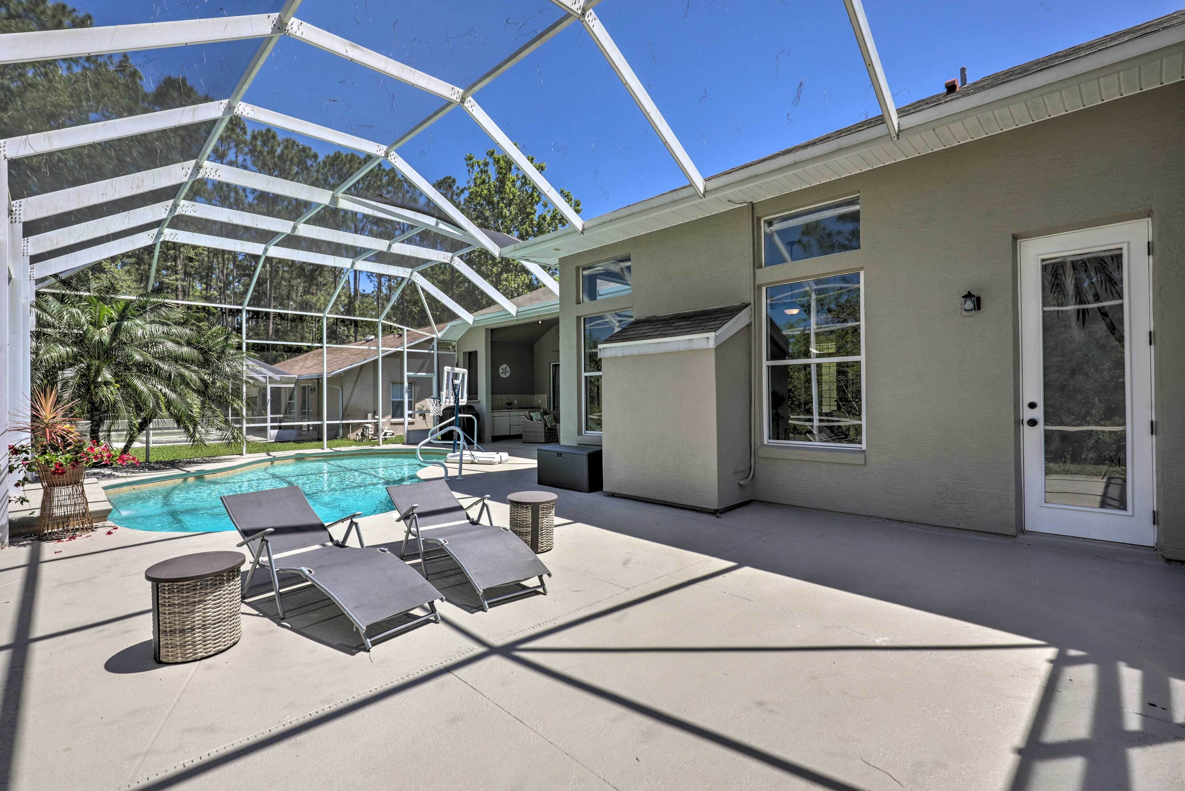A covered outdoor area with a pool, lounge chairs, and a pergola structure.
