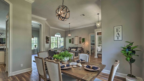 A dining area with a wooden table set for four, surrounded by chairs. There is a chandelier above the table and a potted plant to the side. - Upscale Palm Coast Home w/ Pool: 7 Mi to Beaches! (Palm Coast)