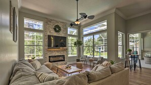 A spacious living room with a large sectional sofa, a fireplace, and a dining area with a table and chairs. - Upscale Palm Coast Home w/ Pool: 7 Mi to Beaches! (Palm Coast)
