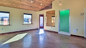 A spacious hallway with a wooden ceiling, large windows, and a green door. - Cozy 'blue Adobe' w/ Steam Room 2 Mi. From Taos! (El Prado)