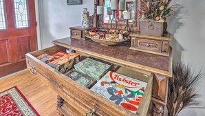 A wooden chest with a game board and a Twister box, a wooden sideboard with decorative items, and a red door.