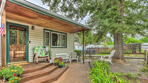 A house with a wooden porch, steps leading to a bench, and potted plants.