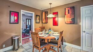 A dining area with a round table set for six, surrounded by wooden chairs with cushioned seats.