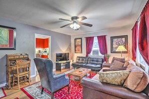 Ein Wohnzimmer mit Deckenventilator, einer Couch, einem Couchtisch und einem Fernseher.