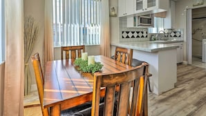 Une cuisine moderne avec des meubles blancs, un îlot central et un coin repas comprenant des chaises et une table en bois.